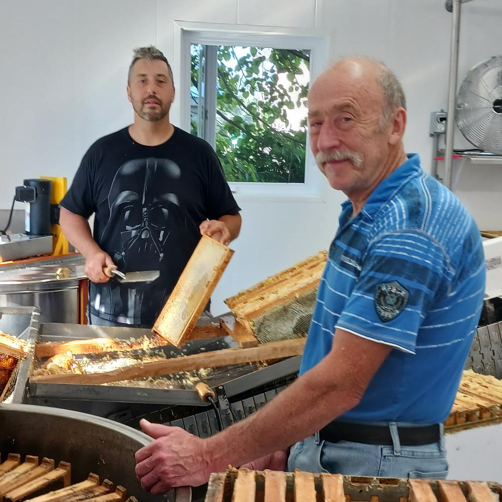Richard Paradis en compagnie de son fils Éric, captés en pleine opération d’extraction du miel. Photo : Roger Lafrance